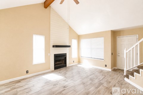A spacious room with a fireplace and a staircase.