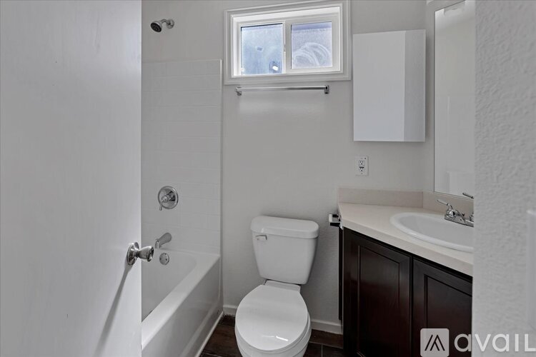 A white toilet in a small bathroom with a window above it.