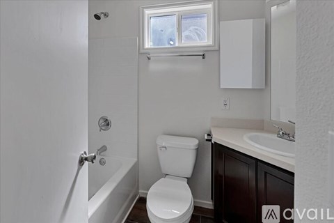 A white toilet in a small bathroom with a window above it.