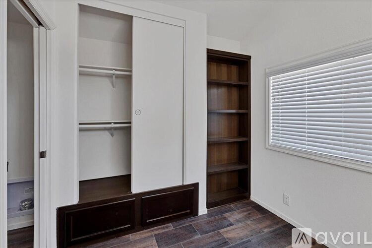 A room with a white door and a brown shelf.