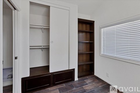 A room with a white door and a brown shelf.