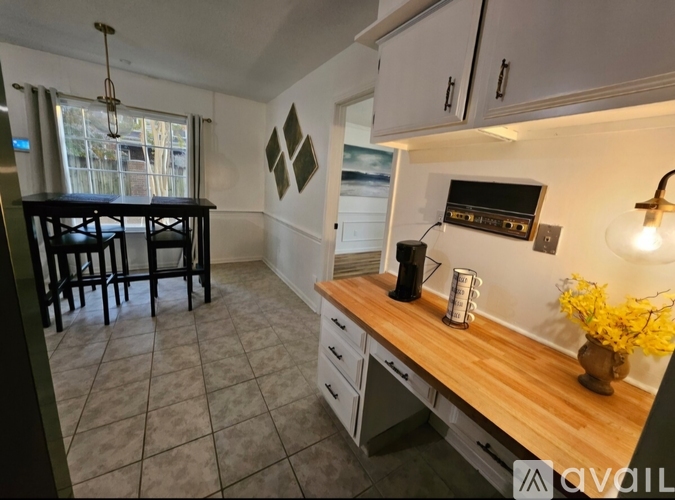 A kitchen with a wooden counter and a dining table with chairs.