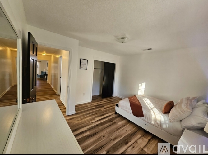 A bedroom with a bed and a wooden floor.