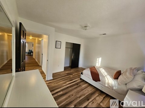 A bedroom with a bed and a wooden floor.