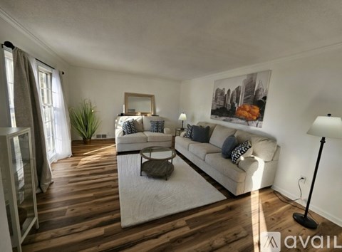 A living room with a white couch and a wooden floor.