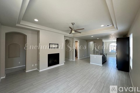 A spacious living room with a fireplace and a ceiling fan.
