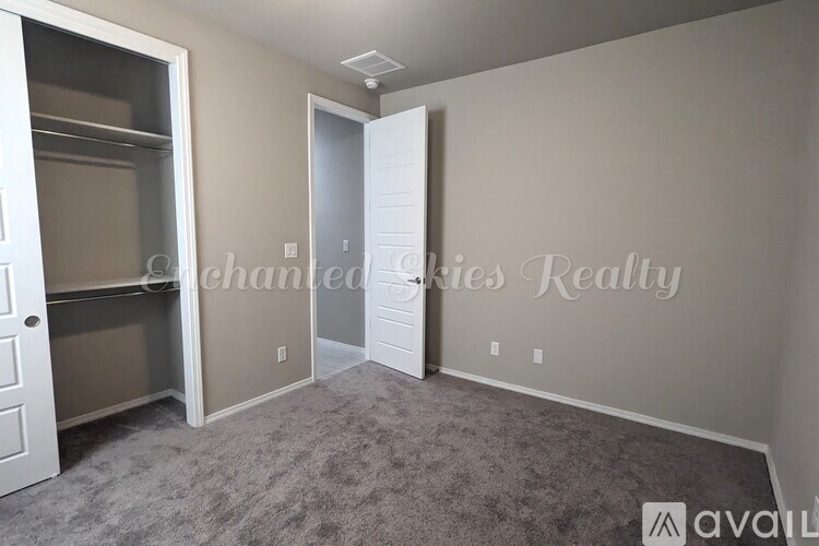 A room with a carpeted floor and two doors, one of which is open.