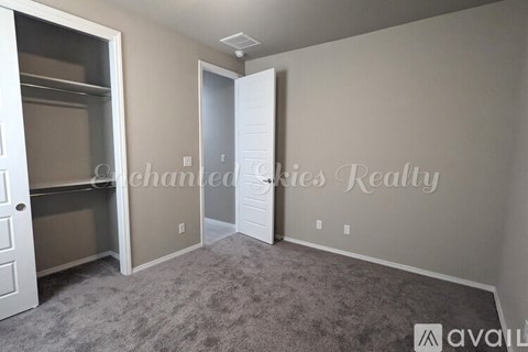 A room with a carpeted floor and two doors, one of which is open.