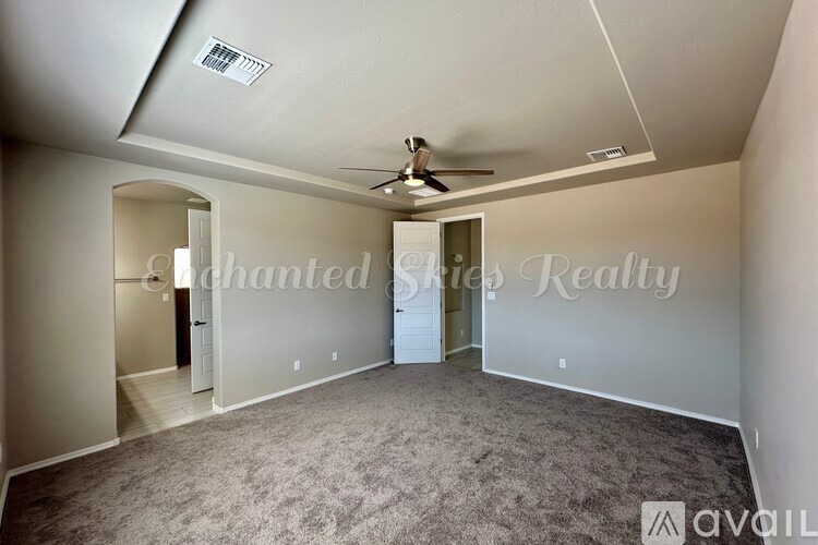 A spacious room with a ceiling fan and carpeted floor.