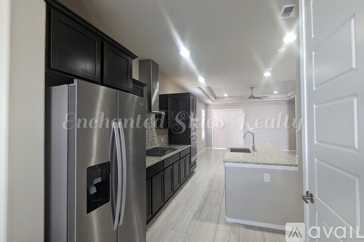 A modern kitchen with a stainless steel refrigerator and black cabinets.