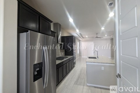 A modern kitchen with a stainless steel refrigerator and black cabinets.