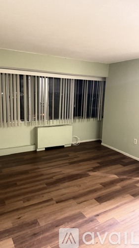 A room with wooden flooring and a window with blinds.