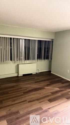 A room with wooden flooring and a window with blinds.