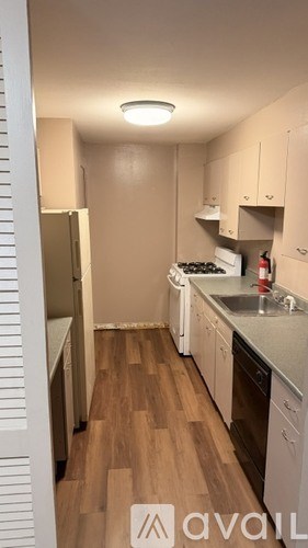 A kitchen with white appliances and wooden floors.