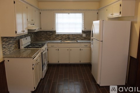 A kitchen with white appliances and brown tile flooring.