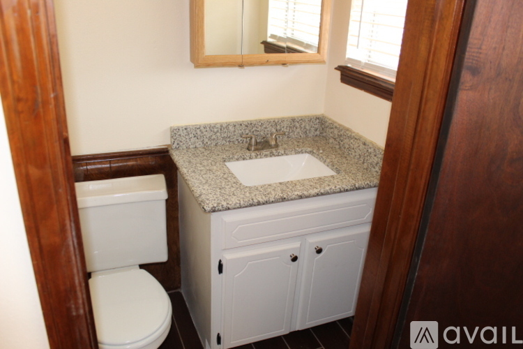A bathroom with a toilet, sink, and mirror.