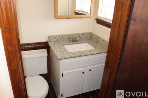 A bathroom with a toilet, sink, and mirror.