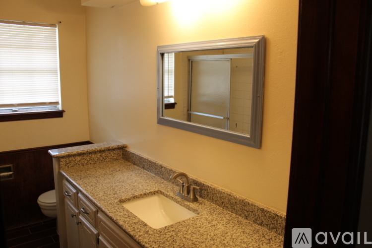 A bathroom with a granite countertop and a mirror above the sink.