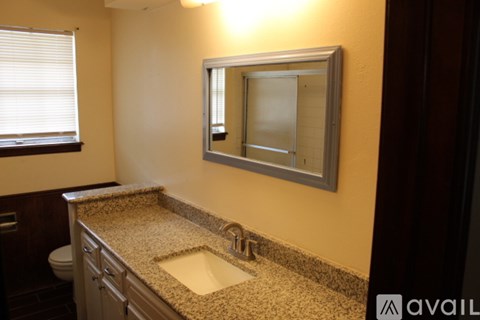 A bathroom with a granite countertop and a mirror above the sink.