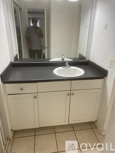 A man is taking a picture in a bathroom with a sink and mirror.