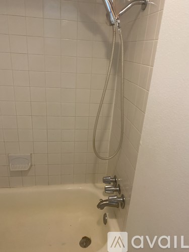 A white bathroom with a white tub and a white shower head.