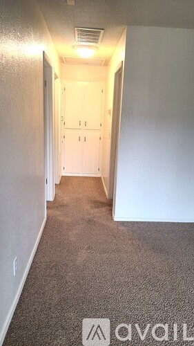A hallway with a carpeted floor and white walls.