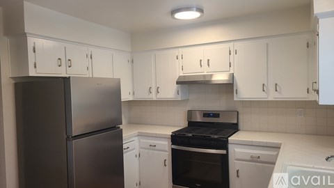 A kitchen with white cabinets and a black stove top oven.