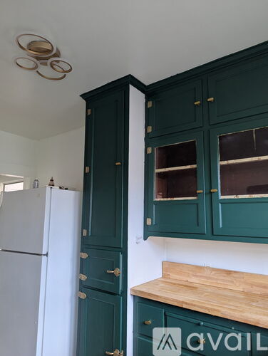 A kitchen with green cabinets and a white fridge.