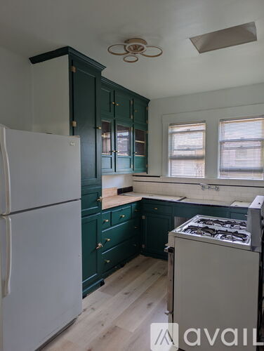 A kitchen with green cabinets and a white refrigerator.