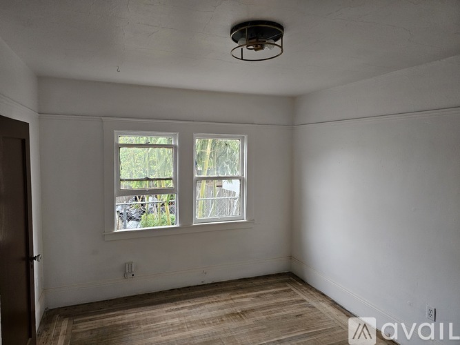 A room with a wooden floor and two windows.