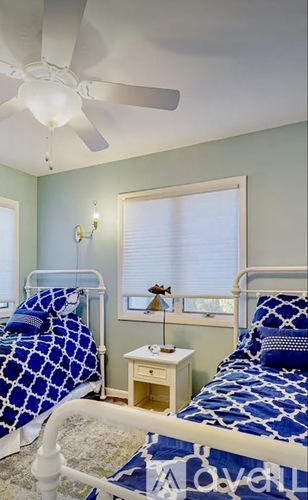 A bedroom with two beds and a ceiling fan.