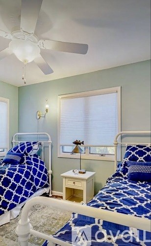 A bedroom with two beds and a ceiling fan.