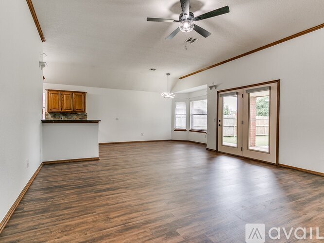 A spacious room with wooden floors and a ceiling fan.