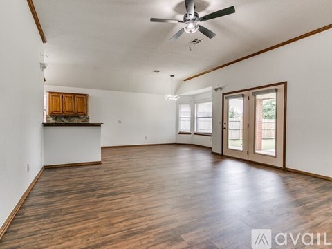 A spacious room with wooden floors and a ceiling fan.