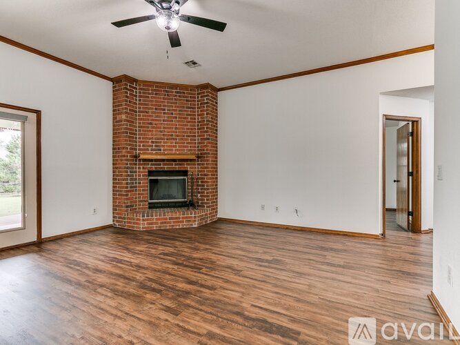 A living room with a brick fireplace and wood flooring.