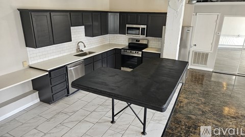 A kitchen with black cabinets and a black table.