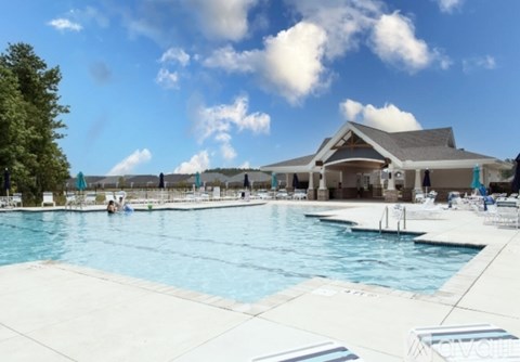 A large swimming pool with people in it and a building in the background.