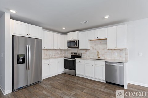 A kitchen with white cabinets and a stainless steel refrigerator.