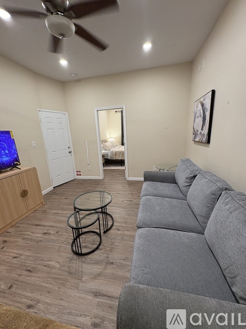 A living room with a grey couch and a ceiling fan.
