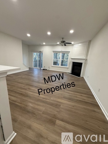 A spacious room with wood flooring and a ceiling fan, labeled with "MDW Properties".