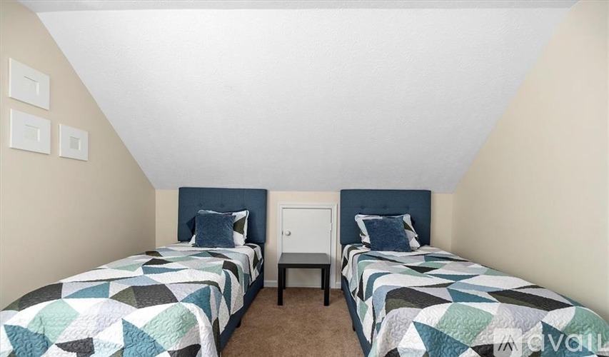 A bedroom with two beds and a nightstand.