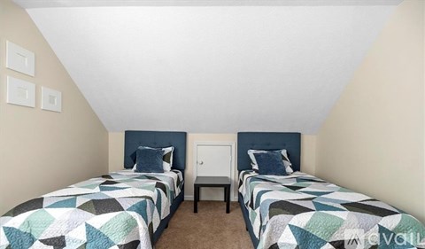 A bedroom with two beds and a nightstand.