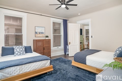 A bedroom with two beds and a ceiling fan.
