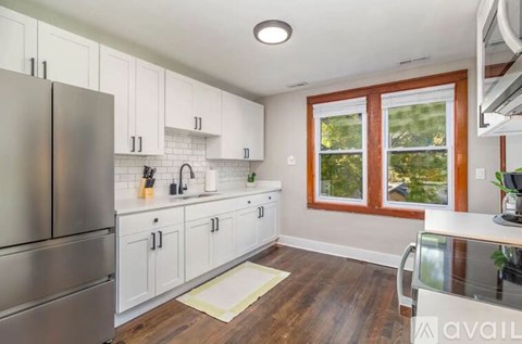 A kitchen with white cabinets and a stainless steel refrigerator.