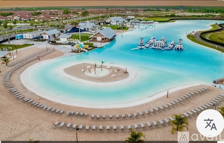 A large swimming pool with a small island in the middle and a water slide.