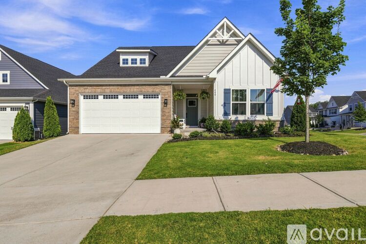 A house with a garage and a tree in front.
