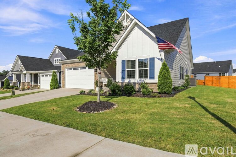 A house with a flag on the front and a tree in the front yard.
