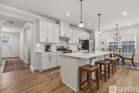 A kitchen with white cabinets and a wooden floor.