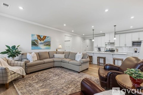 A living room with a brown leather couch and a painting of a bird on the wall.