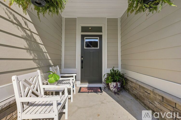 A small porch with a white chair and a green plant.